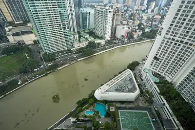 a river with a boat in the middle of a city at Cozy Crib at Acqua Residences - Rockwell Views in Manila