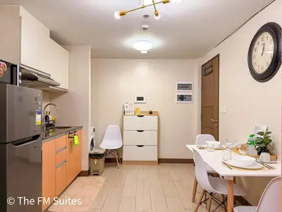 a kitchen with a table and a clock on the wall at Cozy and Spacious Fast WiFi FREE Access Pool and Gym in Manila