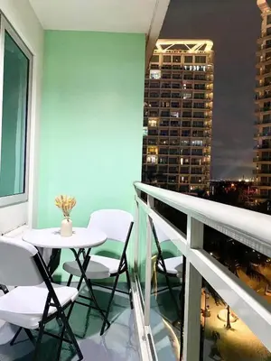 a balcony with a table and chairs and a city at Positano Tower Beach view with PS4 - Azure Parañaque Resort in Manila