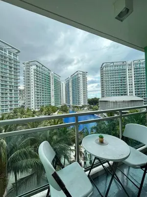 a balcony with a table and chairs and some buildings at Positano Tower Beach view with PS4 - Azure Parañaque Resort in Manila