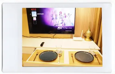 a table with two plates and a tv in a room at Luxe Studio at Fame Residences Malls, CBDs and More in Manila