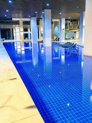 a swimming pool with a blue tile floor in a building at Staycation in Diamond in Manila