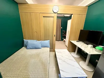 a room with a bed and a desk and a clock at Kathys Crib 11th flr 2 at Shell Residence pool view in Manila