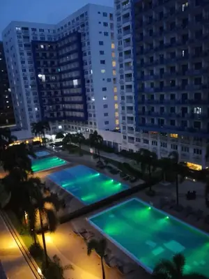 a view of two pools in a city at night at Sea Residence Condotel Pasay in Manila