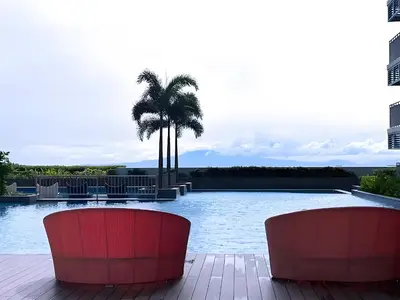 a swimming pool with two red chairs and a palm tree at Luxurious Modern 2 Bedrooms Facing Manila Bay Sunset, Airports, Okada, Solaire, MOA with free parking in Manila