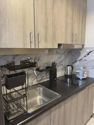 a kitchen with a stainless steel sink and wooden cabinets at Cozy Minimalist Staycation in Manila