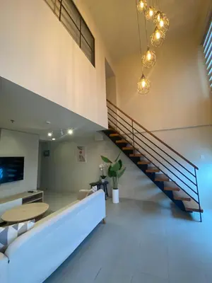a living room with a staircase and a table at EDSA Heights Ama Tower Unit 3305 Loft Penthouse Unit in Manila