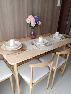 a wooden table with plates and a vase of flowers at Horizon Haven in Manila