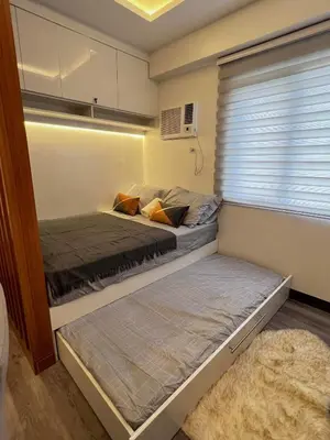 two beds in a small room with a window at Staycation at JG in Manila