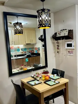 a dining room table with a mirror and a kitchen at One Palmtree Villas in Manila