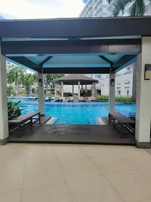 a pavilion with two benches and a swimming pool at Shell residences Moa Staycation by jeric in Manila