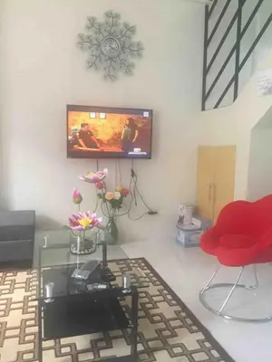 a living room with a red chair and a flat screen tv at Furnished 2BR Apartment in Paradahan
