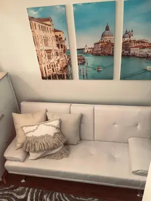 a white couch in a room with three paintings on the wall at Staycation in Bloom in Manila