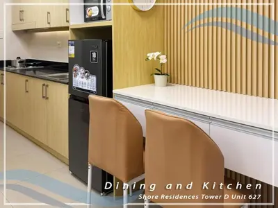 a kitchen with a counter with two chairs and a refrigerator at GV Holiday Homes - Shore Residences MOA - Cozy 1BR Apartment in Manila