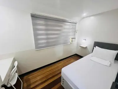 a small bedroom with a white bed and a window at Layover at 1146 in Manila