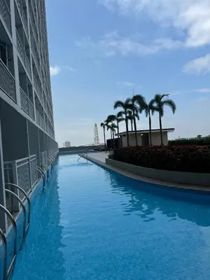 a swimming pool with palm trees next to a building at Juvrey Studio-Unit Breeze Residences in Manila