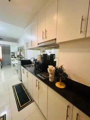 a kitchen with white cabinets and a black counter top at Allie's Cozy Place in Manila
