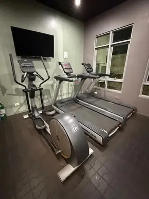 a gym with a treadmill and a flat screen tv at Convertible Double Studio in Salcedo Village in Manila