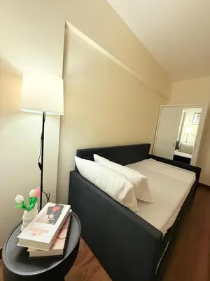 a bed with a black headboard and a table with books at Staycacia Haven 2BR Condo Maple Acacia Taguig in Manila
