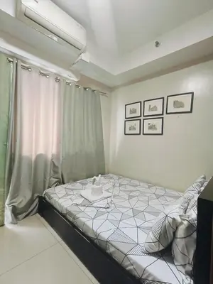 a bedroom with a bed with a table on it at Shell Residences Mall of Asia by Jhem in Manila
