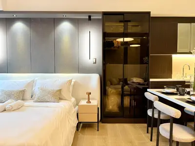 a bedroom with a white bed and a kitchen at Venice Canal View with Balcony near BGC and Airport 10c in Manila