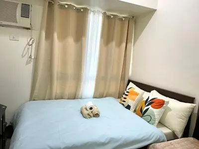 a bed with a stuffed animal on it in front of a window at Minimalist Cozy condo in Makati,Netflix,Sauna,Pool in Manila