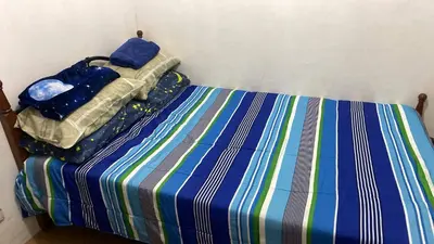 a bedroom with a bed with a striped sheets at 1 Bedroom Townhouse with Airconditon ,Water heater and free wifi,fully furnished in San Roque