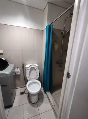 a bathroom with a toilet and a blue shower curtain at Buong tuluyan sa Pasay in Manila