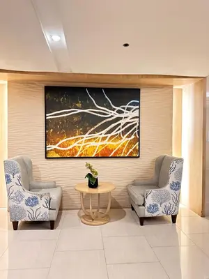 two chairs and a table in a room with a painting at Shell Residences MOA Paul's Place in Manila