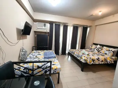 a small room with two beds and a television at Asthrea Condotels in front of NAIA Terminal 3 Airport in Manila