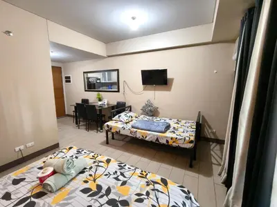 a bedroom with two beds and a dining room at Asthrea Condotels in front of NAIA Terminal 3 Airport in Manila