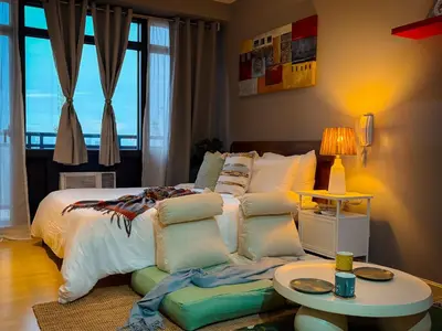 a bedroom with a bed with a table and a couch at Hidden Village at Gramercy Residences - APARTMENT with Infinity Pool Sauna Gym in Manila