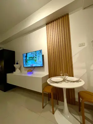 a dining room with a table and a tv at Lush Urban Studio in Manila