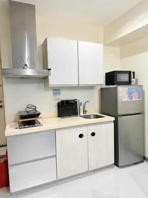 a kitchen with white cabinets and a stainless steel refrigerator at Azure staycation By Icay in Manila