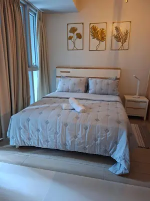a bed with a blue comforter in a bedroom at Mysuites2go24K Parksuites T2 in Manila