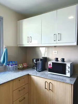 a kitchen with white cabinets and a microwave at 2BR at Bayshore 2 Near Okada & Airport in Manila