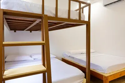 two bunk beds in a dorm room with white sheets at Ephram House - A-Frame Cabin Staycation with Pool, Games & BBQ For Up To 20 Guests in Bacoor