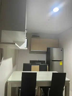 a kitchen with a table with chairs and a refrigerator at 1 BR Unit at Park West - BGC in Manila