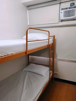 a bunk room with two bunk beds and a fan at Charming 2BR Condo in Cambridge with WIFI, Smart TV in Cainta