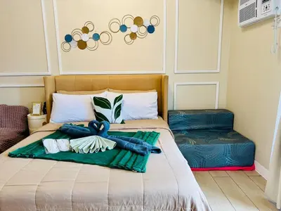 a bed with a green blanket and jeans on it at Cozy Studio Near Venice Mall Netflix WIFI in Manila