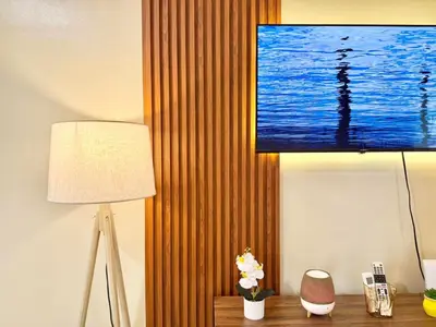 a room with a lamp and a television on a wall at Santis Place at Eighty One Newport Blvd Across NAIA Terminal 3 in Manila