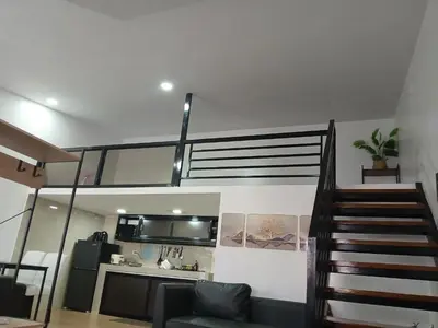 a living room with a staircase leading up to a loft at Stayover Transient House in Carmen