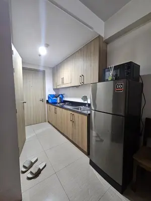 a kitchen with a stainless steel refrigerator and wooden cabinets at Shore Residences Sm Mall of Asia Caitlin in Manila