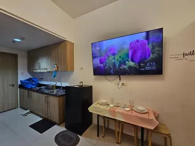a kitchen with a table and a tv on the wall at Shore Residences Sm Mall of Asia Caitlin in Manila