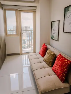a living room with a couch with red pillows at The Bat Cave 3 at Coast Residences Pasay in Manila