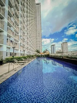 a large swimming pool next to a tall building at The Bat Cave 3 at Coast Residences Pasay in Manila
