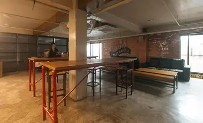a room with a table and benches and a person at RedDoorz Premium at MyTown New York in Manila