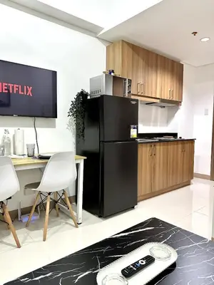 a kitchen with a black refrigerator and wooden cabinets at City SkyView - Level 24 - Pool - Lush Residences in Manila