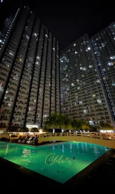 a swimming pool in front of a large building at night at 1BR Unit for 2 pax Makati City in Manila