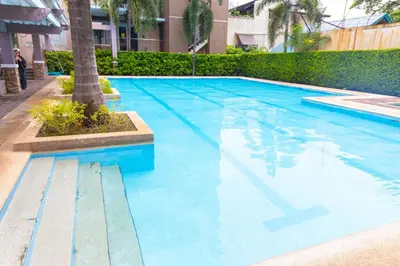 a blue swimming pool with a palm tree next to a building at Air Bel & Be! Your space, Your calm, Your comfort in Manila